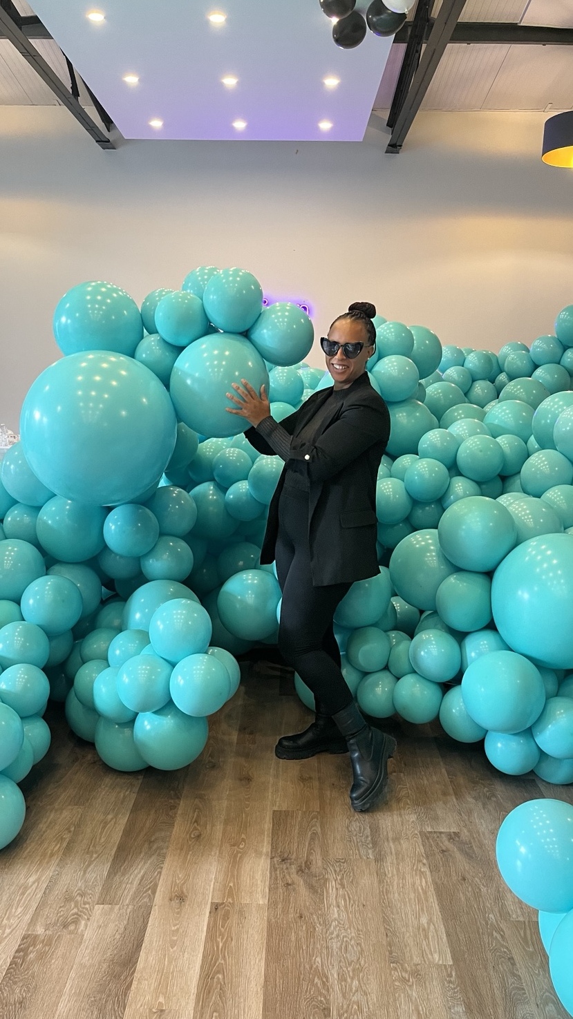 Elysia at work among a large turquoise balloon installation in a venue.